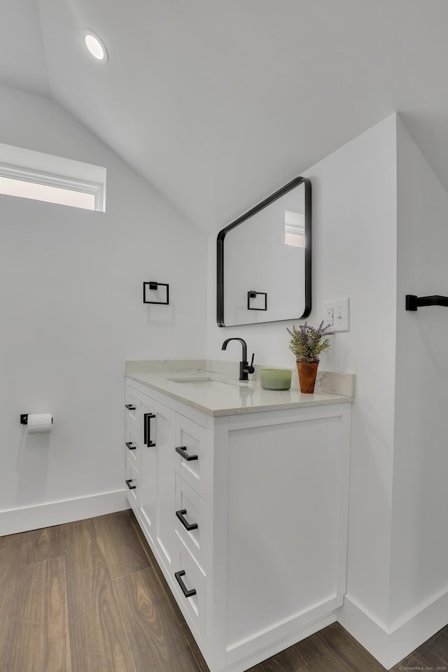 bathroom with vaulted ceiling, baseboards, vanity, wood finished floors, and recessed lighting