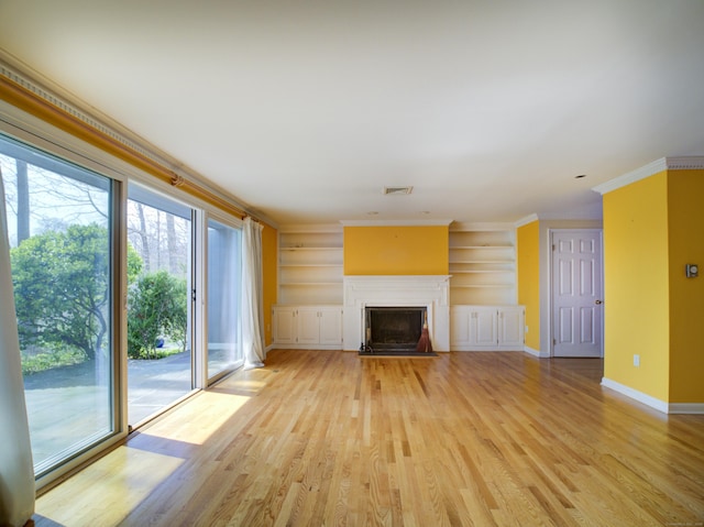 unfurnished living room featuring light wood-type flooring, baseboards, visible vents, built in features, and ornamental molding