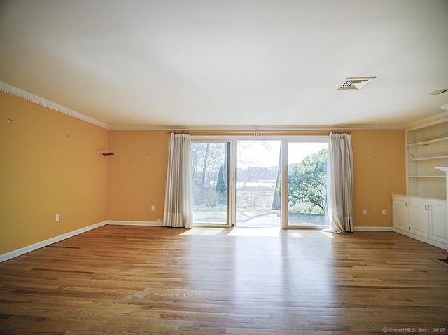 unfurnished room with baseboards, visible vents, a wealth of natural light, and crown molding