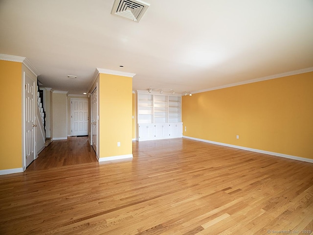 unfurnished room featuring baseboards, crown molding, visible vents, and light wood-style flooring