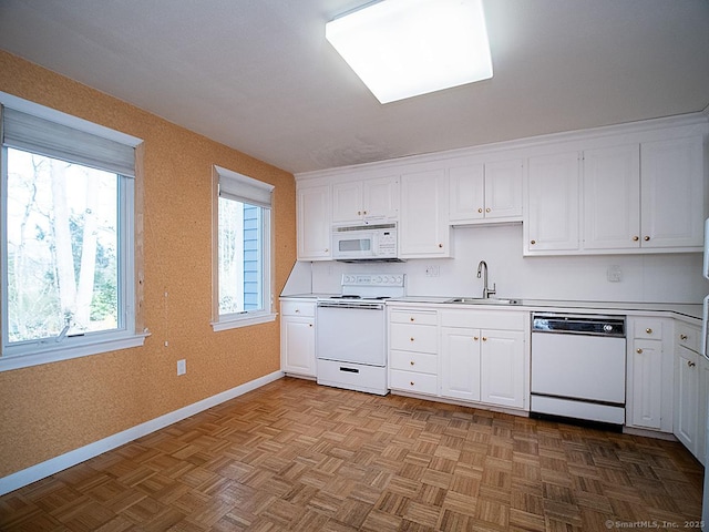 kitchen featuring light countertops, a sink, white appliances, baseboards, and white cabinetry
