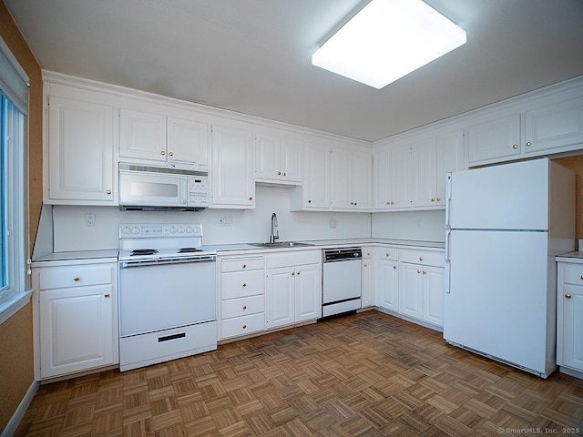 kitchen with white cabinets, light countertops, white appliances, and a sink