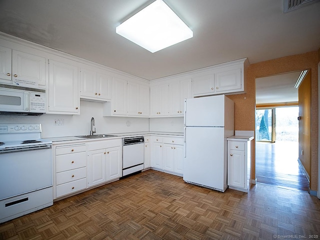 kitchen with a sink, white appliances, light countertops, white cabinets, and visible vents