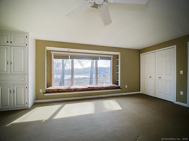 unfurnished bedroom featuring dark colored carpet, a closet, baseboards, and ceiling fan