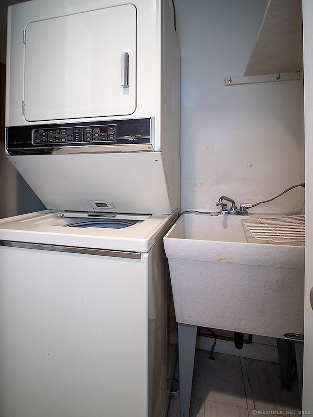clothes washing area featuring stacked washer and dryer, a sink, and laundry area