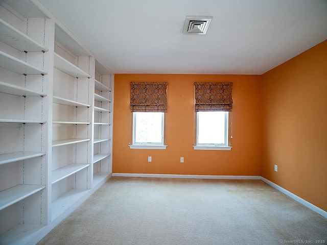 spare room featuring carpet floors, visible vents, and baseboards
