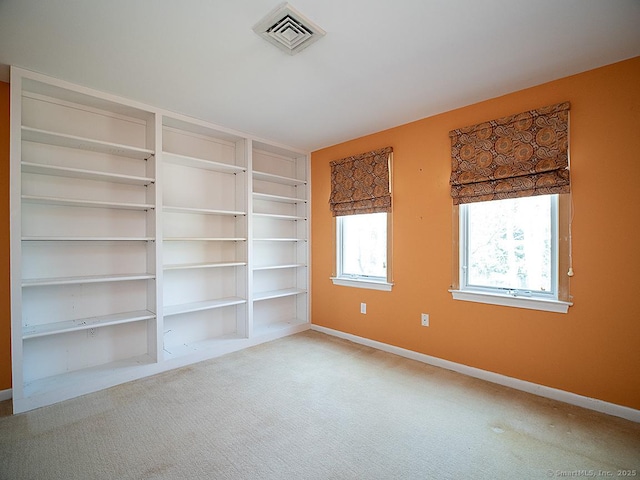 spare room with baseboards, visible vents, built in features, and carpet flooring