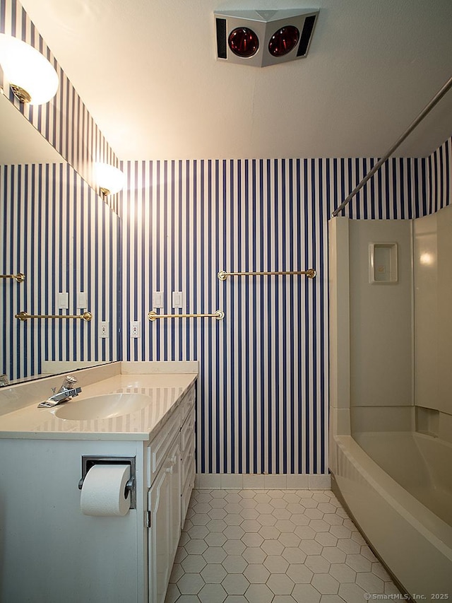 bathroom featuring wallpapered walls, tile patterned floors, vanity, tub / shower combination, and baseboards