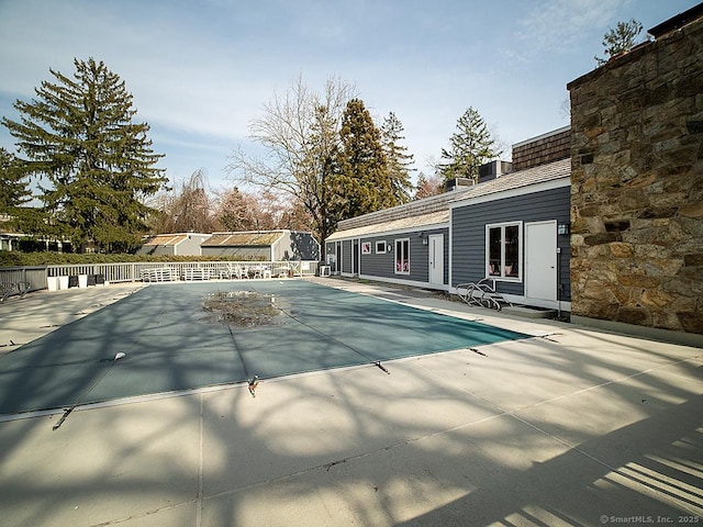 community pool with fence and a patio area