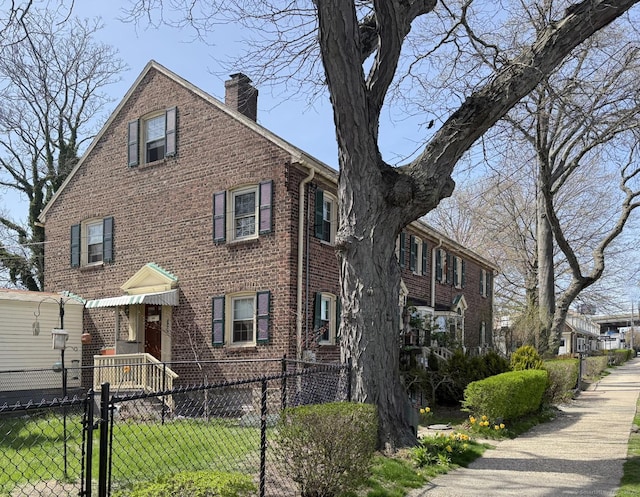 view of property featuring a chimney, brick siding, fence private yard, and a gate