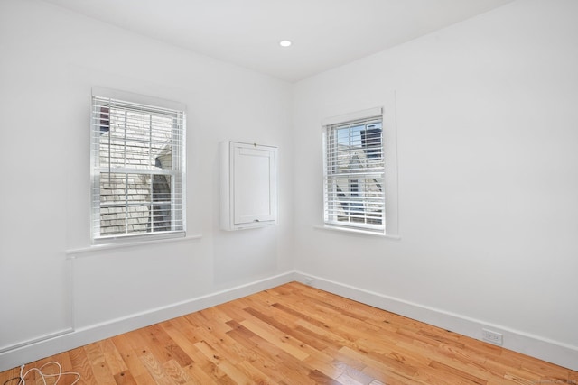 spare room with baseboards, recessed lighting, and light wood-style flooring