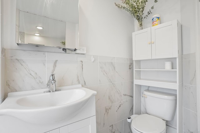 bathroom featuring toilet, tile walls, and vanity