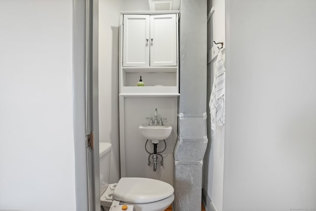 bathroom featuring visible vents, toilet, and a sink