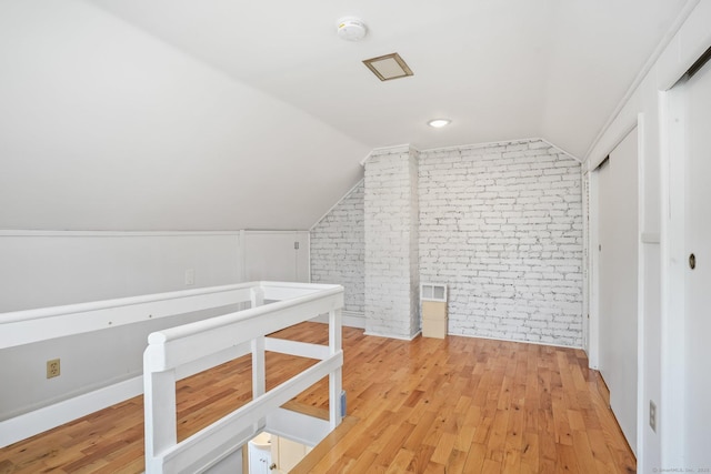 bonus room with visible vents, light wood-type flooring, lofted ceiling, and brick wall