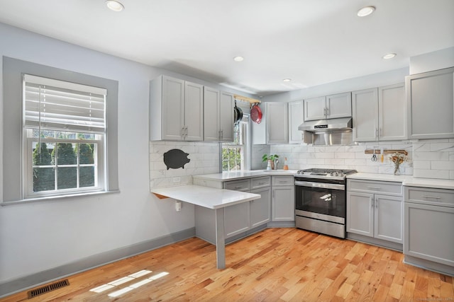 kitchen featuring gray cabinetry, stainless steel gas range, a healthy amount of sunlight, and under cabinet range hood