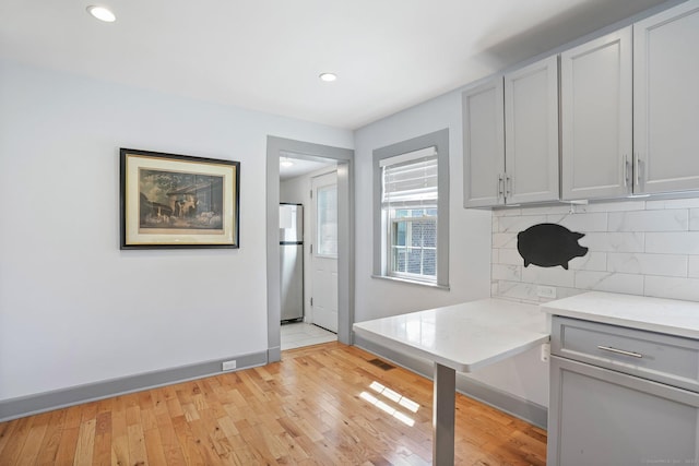 kitchen with tasteful backsplash, recessed lighting, light wood-style flooring, freestanding refrigerator, and light countertops