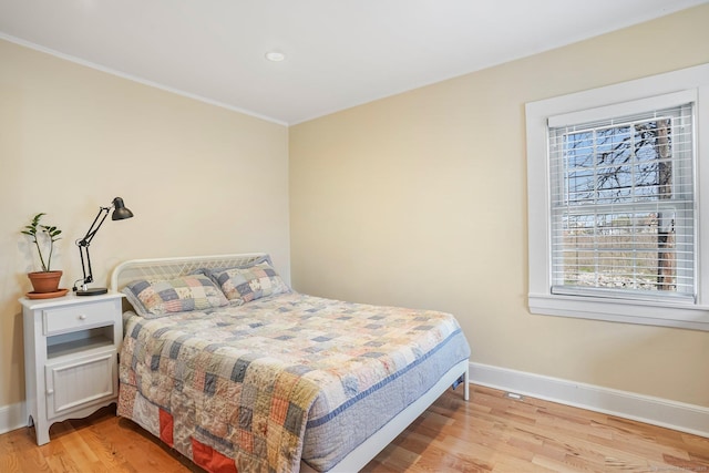 bedroom with crown molding, light wood finished floors, and baseboards