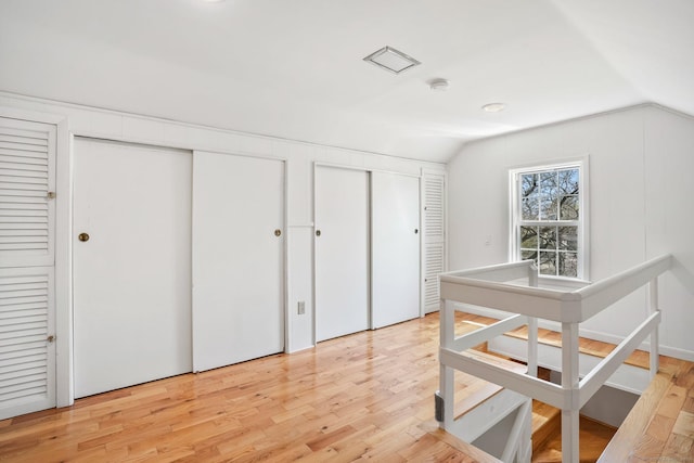 interior space with lofted ceiling, multiple closets, and light wood-style flooring