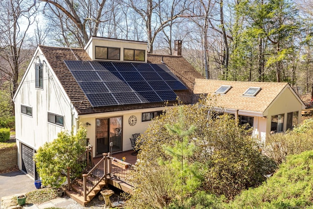 206 New Rd, Avon, CT 06001 - view of front of house featuring roof mounted solar panels, roof with shingles, an attached garage, and a chimney