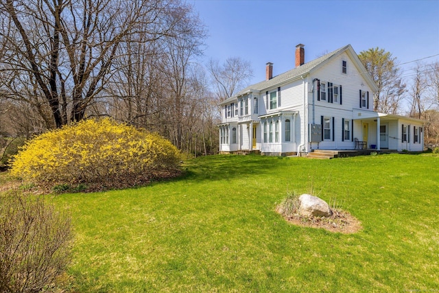 back of property featuring a chimney and a yard