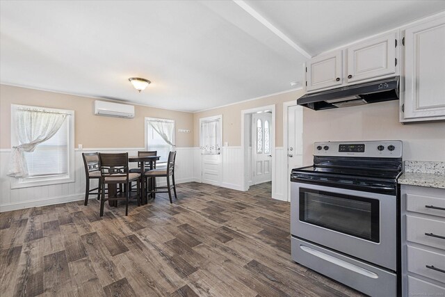 kitchen featuring electric range, a wall unit AC, under cabinet range hood, and dark wood finished floors
