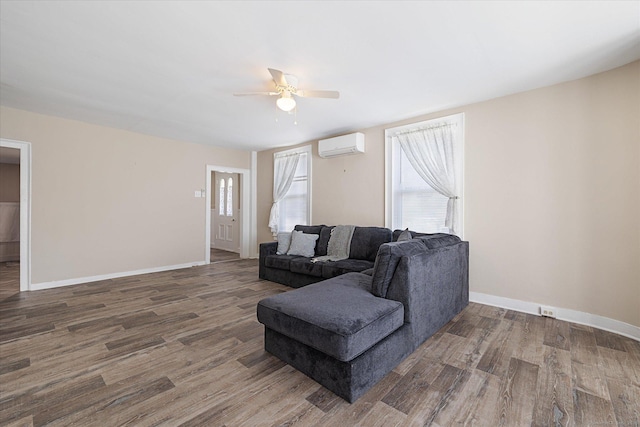 living area with baseboards, a wall mounted air conditioner, ceiling fan, and wood finished floors