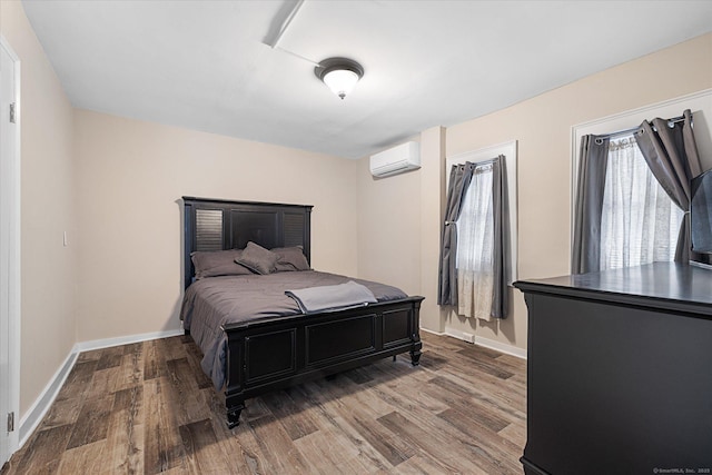bedroom with baseboards, a wall mounted AC, and wood finished floors