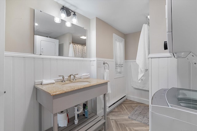 full bathroom featuring a sink, a wainscoted wall, a baseboard radiator, and a decorative wall