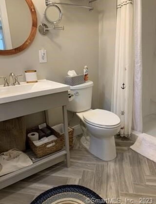 bathroom featuring toilet, a shower stall, and vanity