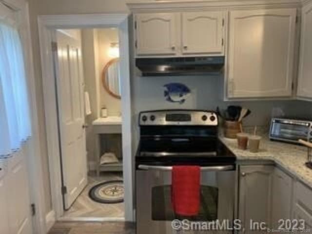 kitchen with a toaster, under cabinet range hood, and electric stove