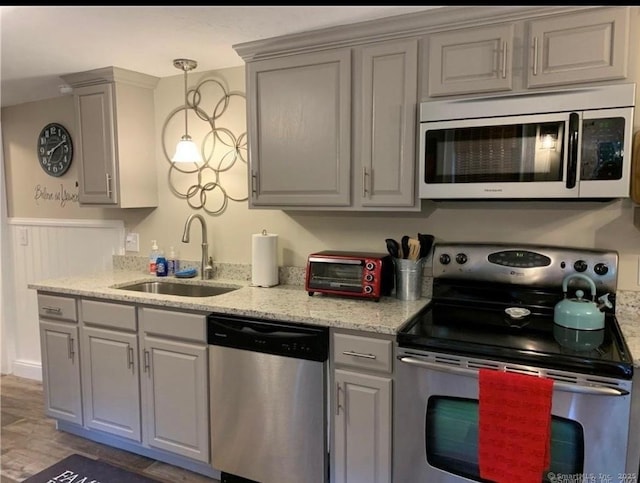 kitchen with a toaster, light wood-type flooring, gray cabinets, a sink, and appliances with stainless steel finishes