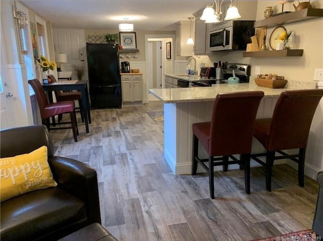 kitchen featuring a sink, light wood finished floors, stainless steel appliances, and a peninsula