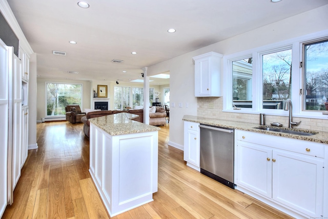 33 Pequot Trl, Westport, CT 06880 - kitchen with dishwasher, a sink, a fireplace, open floor plan, and white cabinets