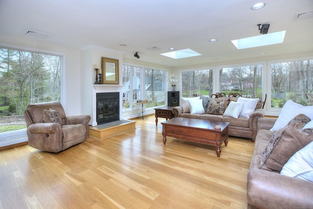 33 Pequot Trl, Westport, CT 06880 - living room featuring a skylight, light wood-style floors, a glass covered fireplace, plenty of natural light, and recessed lighting