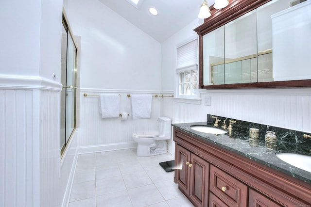33 Pequot Trl, Westport, CT 06880 - full bath featuring a wainscoted wall, tile patterned flooring, vaulted ceiling, double vanity, and toilet