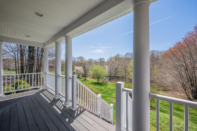 wooden deck featuring covered porch and a lawn