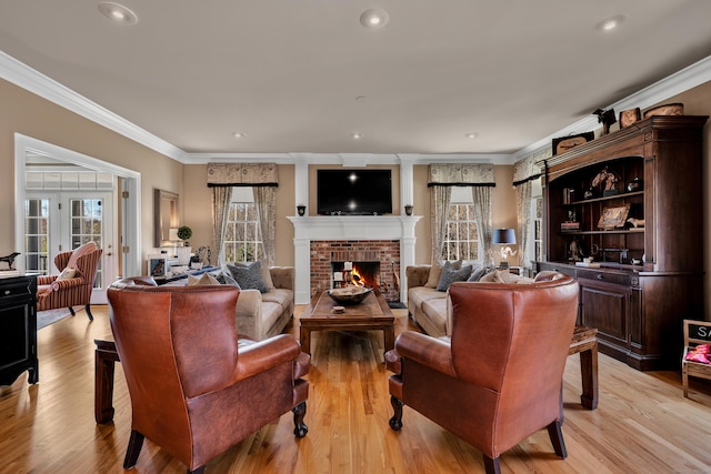 living room with crown molding, recessed lighting, a brick fireplace, and light wood-type flooring