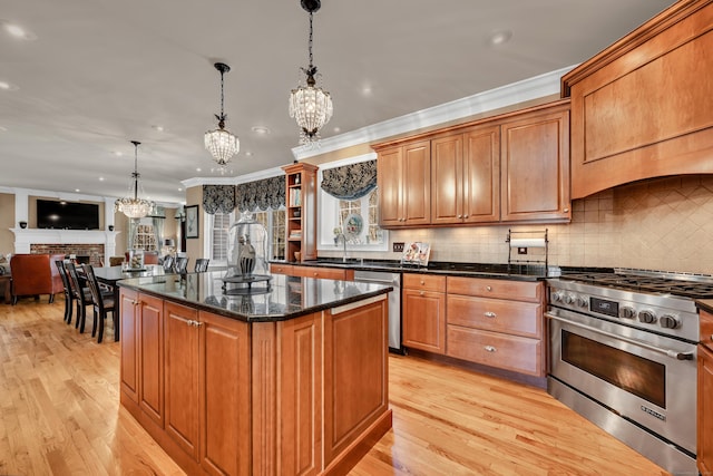 kitchen featuring crown molding, a kitchen island, light wood-style floors, appliances with stainless steel finishes, and a notable chandelier