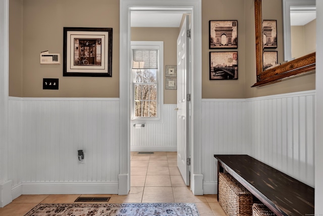 interior space with a wainscoted wall, light tile patterned flooring, and visible vents