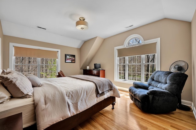 bedroom featuring visible vents, light wood-style flooring, lofted ceiling, and multiple windows