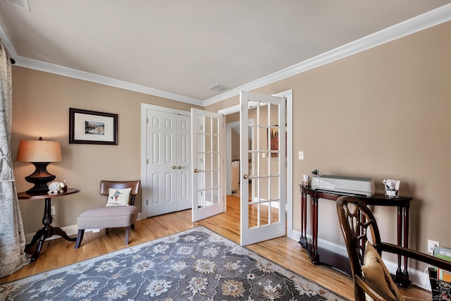 sitting room featuring french doors, ornamental molding, baseboards, and wood finished floors