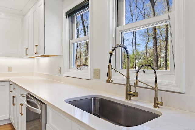 kitchen with light countertops, white cabinetry, a sink, and dishwasher