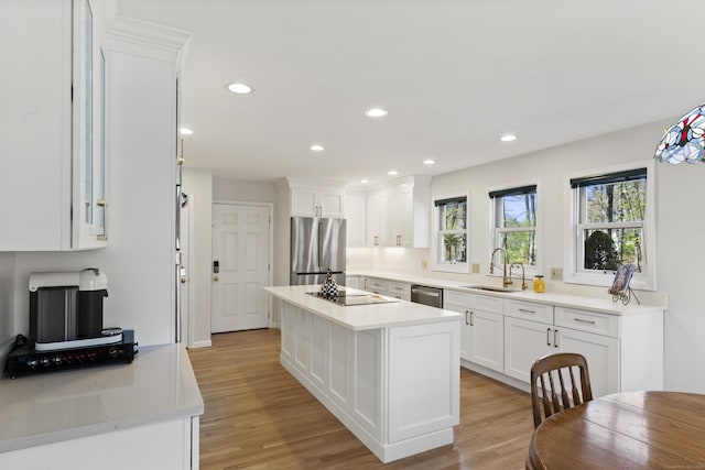 kitchen with a sink, light wood-style flooring, stainless steel appliances, and white cabinetry