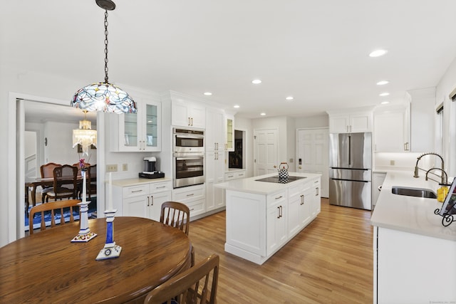 kitchen featuring a center island, light countertops, light wood-type flooring, a sink, and appliances with stainless steel finishes