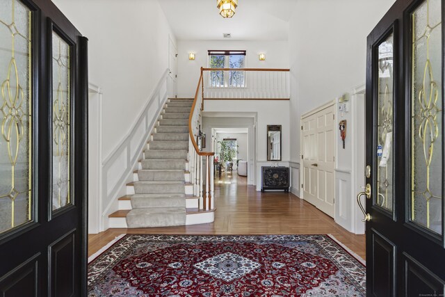 foyer entrance featuring a high ceiling, wood finished floors, stairway, and a decorative wall