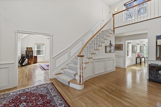 stairway featuring a high ceiling, a decorative wall, and a wealth of natural light