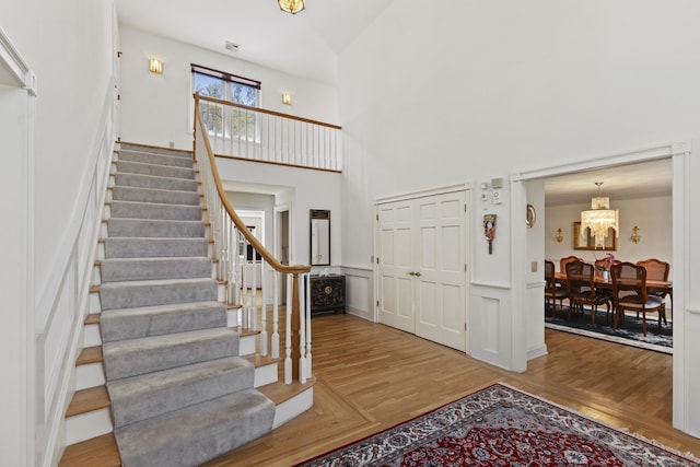 foyer featuring stairs, a high ceiling, a chandelier, and wood finished floors