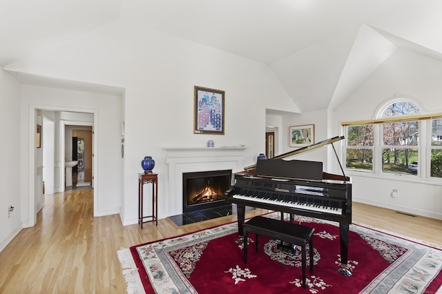 living area featuring baseboards, a fireplace with flush hearth, wood finished floors, and lofted ceiling