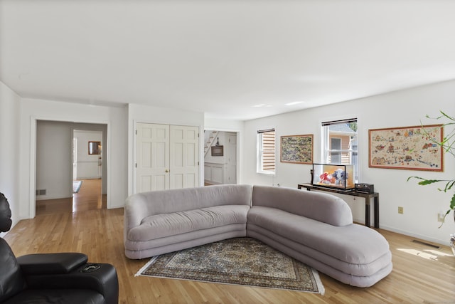 living area with visible vents, baseboards, and wood finished floors
