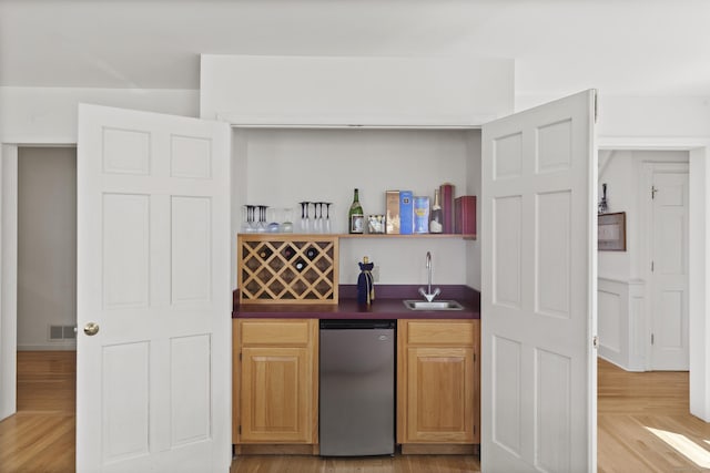 bar featuring visible vents, refrigerator, light wood-style flooring, a sink, and wet bar